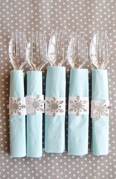 four blue napkins with silver snowflakes on them are lined up against a polka dot tablecloth