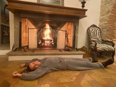 a woman laying on the floor in front of a fire place