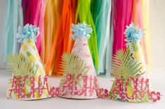 two party hats that say happy birthday and are decorated with pineapples, palm leaves, and flowers