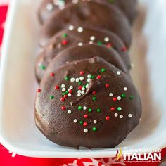 chocolate covered donuts with sprinkles in a white tray on a red tablecloth