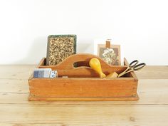 a wooden box with scissors and other items in it on top of a wood table