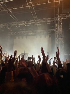 a group of people standing on top of a stage holding their hands up in the air