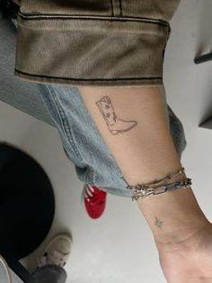 a person with a small tattoo on their arm and foot is wearing a pair of jeans