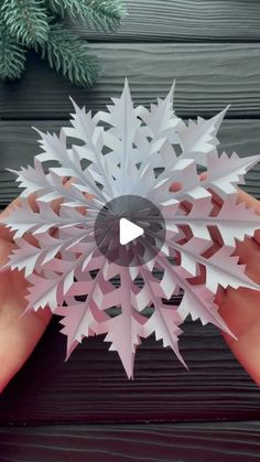 someone holding a paper snowflake in their hand