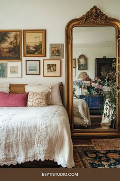 a bed sitting under a large mirror next to a wall mounted with pictures on it