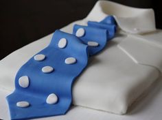 a white shirt with blue and white polka dots on the collar is sitting on a table