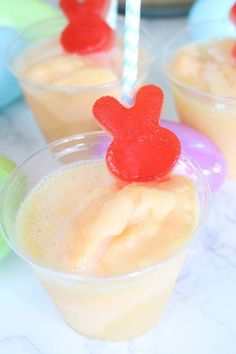 three cups filled with liquid and topped with red hearts on top of each cup are sitting on a table