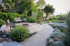 an outdoor patio with seating and trees in the background, surrounded by rocks and plants