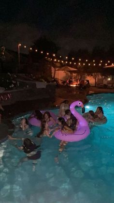 people are in the pool at night with an inflatable flamingo floater