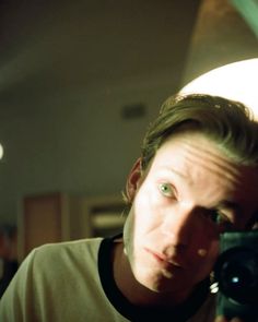 a man holding a camera up to his face in front of a mirror with the light on