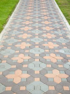 a brick walkway with grass and trees in the background