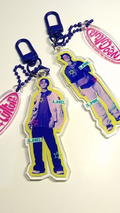 two key chains with tags attached to them on top of a white surface, one has an image of a man in blue and the other is wearing jeans