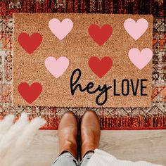 someone standing in front of a door mat that says hey love with hearts on it