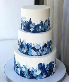 a three tiered cake with blue flowers painted on it