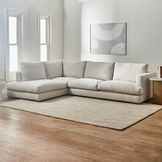 a living room with white furniture and wood flooring, including a large sectional couch