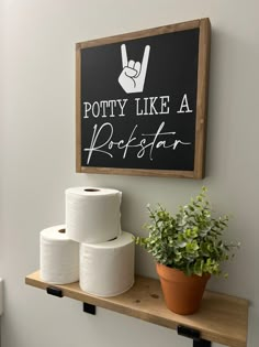 a sign that says potty like a rockstar on the wall above toilet paper