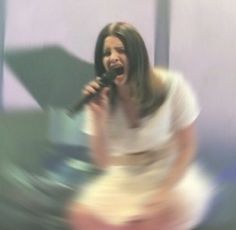 a blurry photo of a woman singing into a microphone