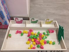 there are many small toys in the box on the floor and one is pink, green, yellow and white