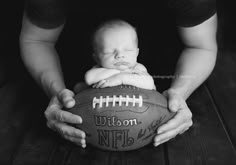 a black and white photo of a baby holding a football with the words welcome in it