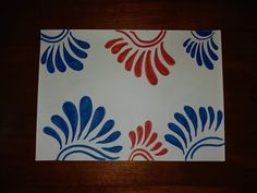 a piece of paper with red, white and blue designs on it sitting on a table