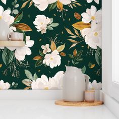 the wallpaper is green with white flowers and leaves on it, along with two mugs