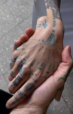 two hands holding each other with tattoos on them