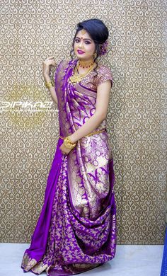 a woman in a purple and gold sari posing for the camera with her hand on her hip