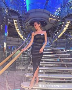 a woman in a black dress standing on some stairs