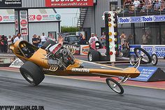 a man riding on the back of a motorcycle in a wheelie course at a drag track