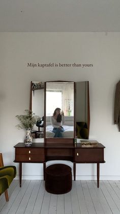 a woman is taking a selfie in the mirror while sitting at a dressing table