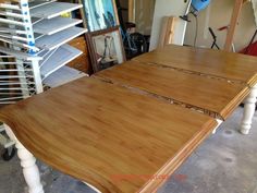 a wooden table with white legs in a room next to other woodworking tools and supplies