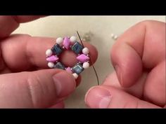 two hands are working on a beaded ring with beads and thread in the middle