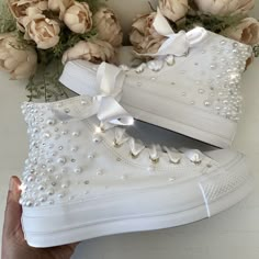 a pair of white high top sneakers with pearls on them