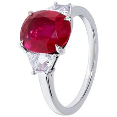 an oval ruby and diamond ring with two pear shaped diamonds on the sides, set in white gold