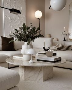 a living room filled with white furniture and a vase on top of a coffee table