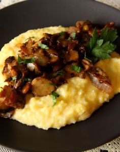 mashed potatoes topped with mushrooms and parsley on a black plate, ready to be eaten