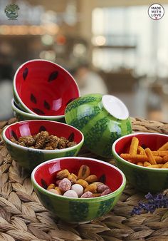 four bowls filled with different types of food on top of a wicker tablecloth