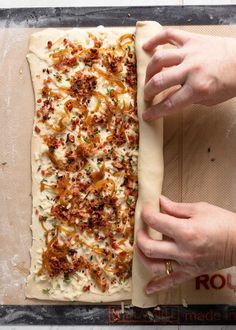 two hands are placing toppings on top of a homemade pizza crust that is ready to go into the oven