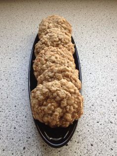 some oatmeal cookies sitting on top of a black spoon in the middle of a counter