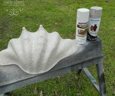 two spray paint bottles sitting on top of a metal bench in the middle of a field