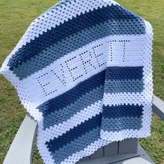 a blue and white crocheted blanket sitting on top of a chair in the grass