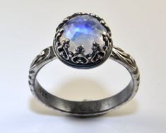 This moonstone ring features a faceted 8mm rainbow moonstone, a romantic piece with a white gemstone that has a nice blue flash. The sterling silver ring features a stone that is set in a beautifully detailed and decorative crown gallery wire. This statement ring is shown oxidized for an antique look, but I can also make it highly polished for a more classic look or for a wedding ring. Please select your preferred finish during the ordering process. The beautiful Renaissance style band with scro Silver Faceted Moonstone Ring For Wedding, Silver Faceted Moonstone Wedding Ring, Faceted Silver Moonstone Wedding Ring, June Birthstone Jewelry, June Birthstone, Jewelry Wedding, Moonstone Ring, June Birth Stone, Look Plus