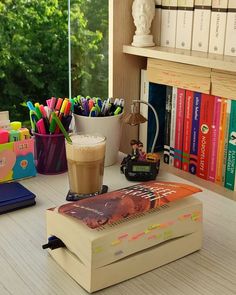 a cup of coffee sitting on top of a book next to a stack of books