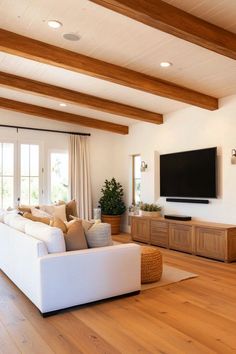 a living room with white couches and wooden beams on the ceiling is shown in front of a flat screen tv