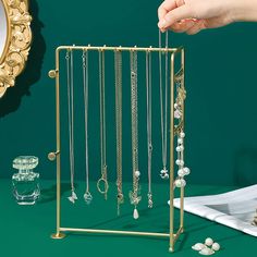 a gold jewelry rack with several necklaces hanging from it and a mirror in the background