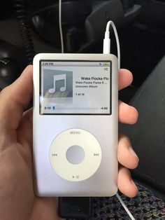 someone holding an ipod in their hand with a mp3 player attached to the back of it