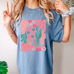 Unleash your free-spirited cowgirl vibes in our Boho Cowgirl T-Shirt. With a touch of boho style, this abstract floral design adds a playful twist to your wardrobe. Perfect for expressing your unique, fun-loving personality. Multicolor Bohemian Relaxed Fit T-shirt, Bohemian Pink Graphic Print T-shirt, Spring Casual T-shirt With Abstract Print, Casual Spring T-shirt With Abstract Print, Bohemian Cotton Tops With Unique Print, Bohemian Cotton Top With Unique Print, Blue Bohemian T-shirt For Summer, Bohemian Blue T-shirt For Summer, Bohemian Spring T-shirt With Graphic Print