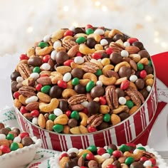 a red and white container filled with lots of candy covered cookies next to other treats