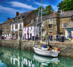 a sailboat is moored in the water next to some old buildings and people