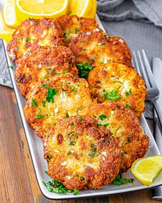 two crab cakes on a plate with lemon wedges